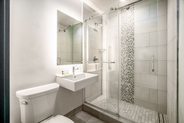 A modern bathroom features a glass-enclosed shower, a white toilet and a wall-mounted sink with a large mirror above it, creating a clean, sleek look.