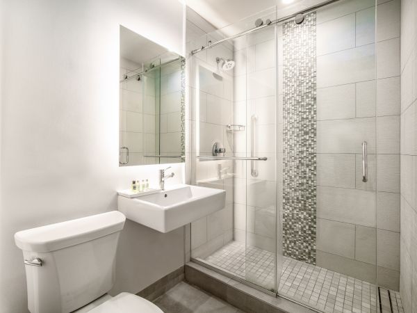 A modern bathroom features a glass-enclosed shower, a white toilet and a wall-mounted sink with a large mirror above it, creating a clean, sleek look.