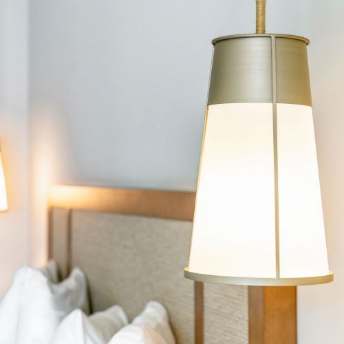 The image shows a modern bedroom with hanging pendant lights and a wooden bed with white pillows and bedding.