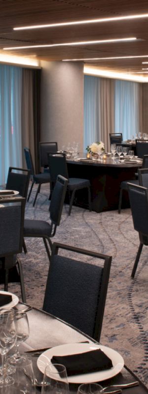 The image shows a decorated banquet hall with round tables set for an event. The round tables are adorned with white flowers and arranged neatly.